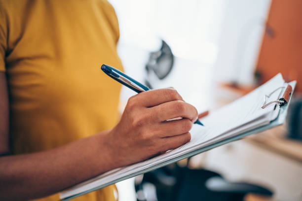 Person filling out form on clipboard