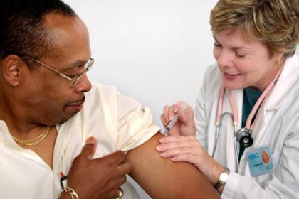 Nurse administering a vaccination to a patient in his left upper arm